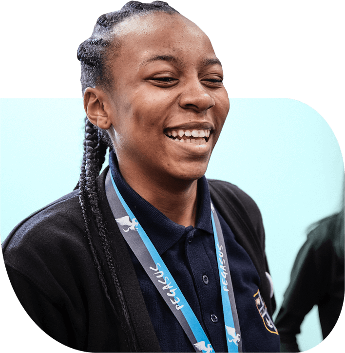 A social entrepreneur with long red hair and a beard uses a drill in a wood workshop.