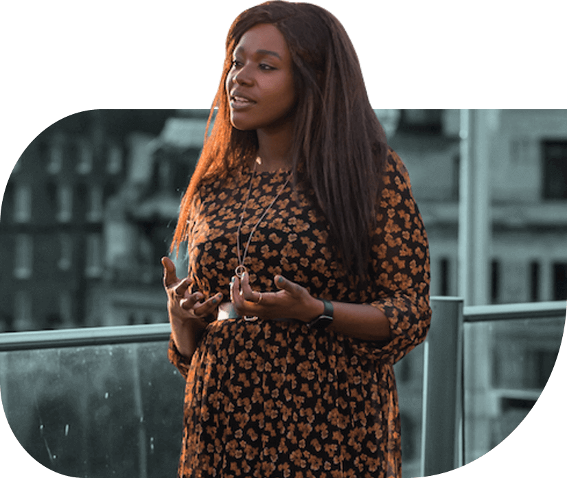 Indie Gordon, Head of Programs at Foundervine is in conversation on a roof terrace. She is Black, has long brown hair and wears a black and orange floral dress.